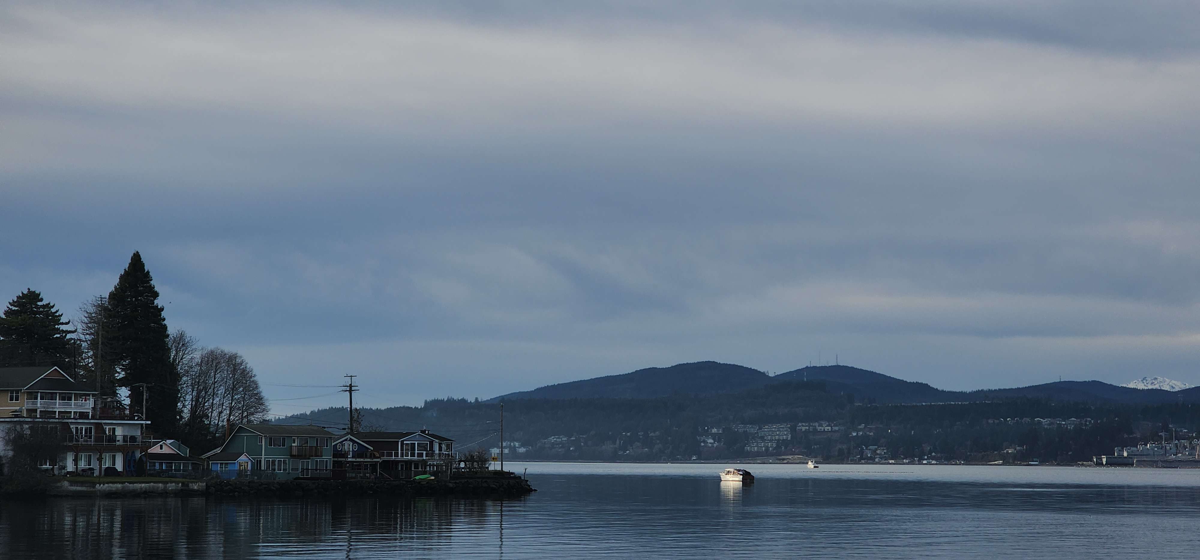 A picture of Washington state's waterside with houses to the left and a boat in the center.