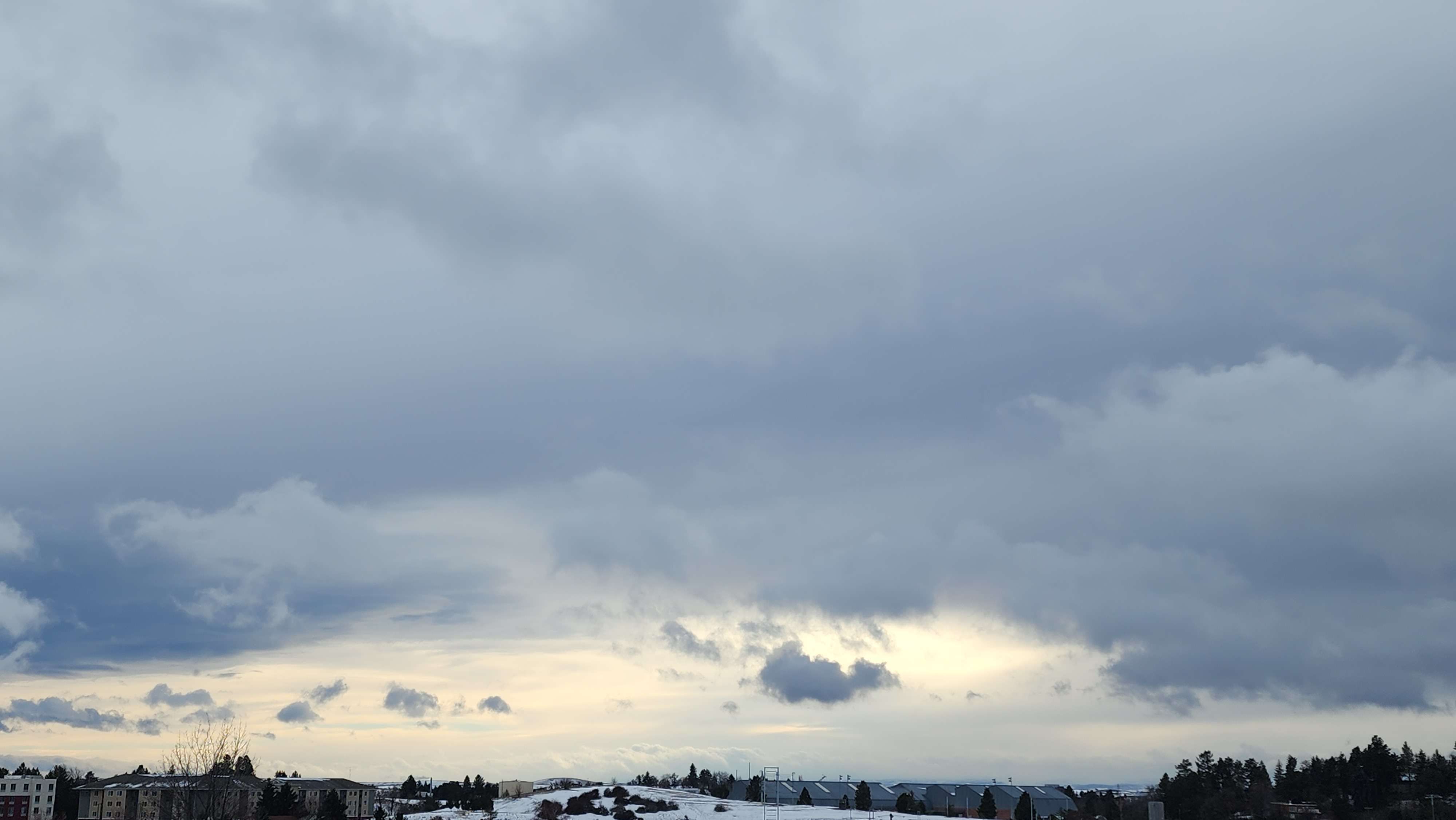 A picture of clouds wit houses and snow on the ground in Pullman Washington.